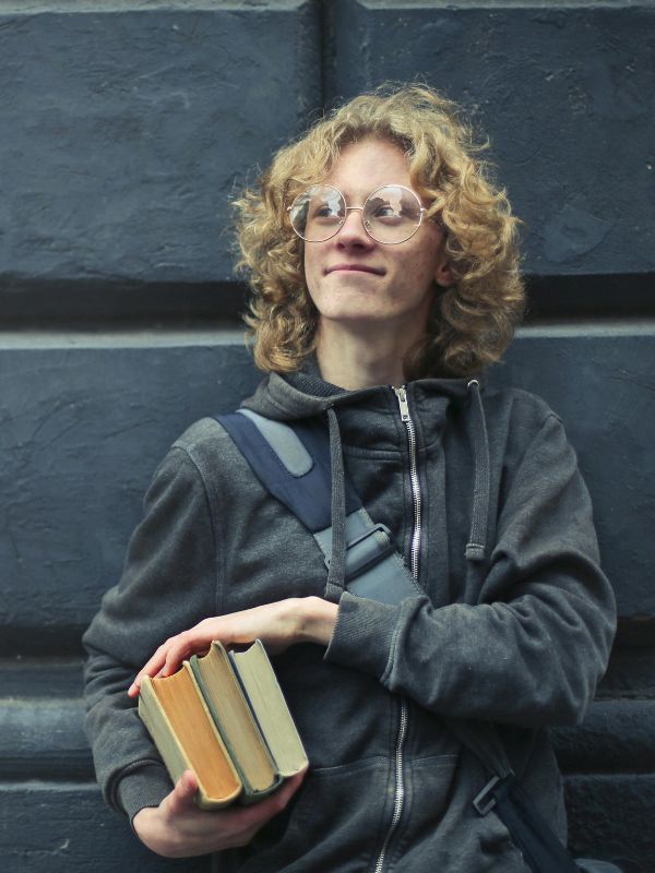 Young adult standing against a wall getting ready for school