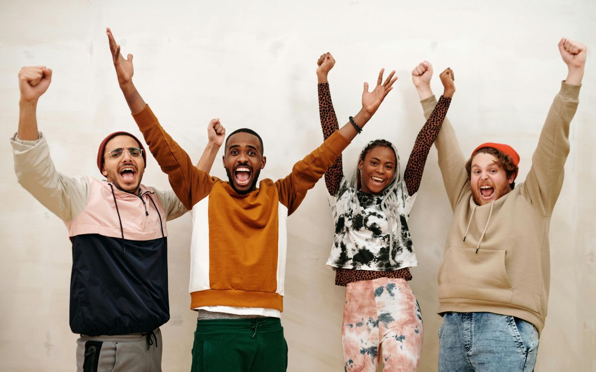 Group of young adults holding their hands up